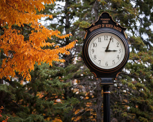Scenic shot of antique outdoor clock. Inscription reads: Founded 1883, University of North Dakota"
